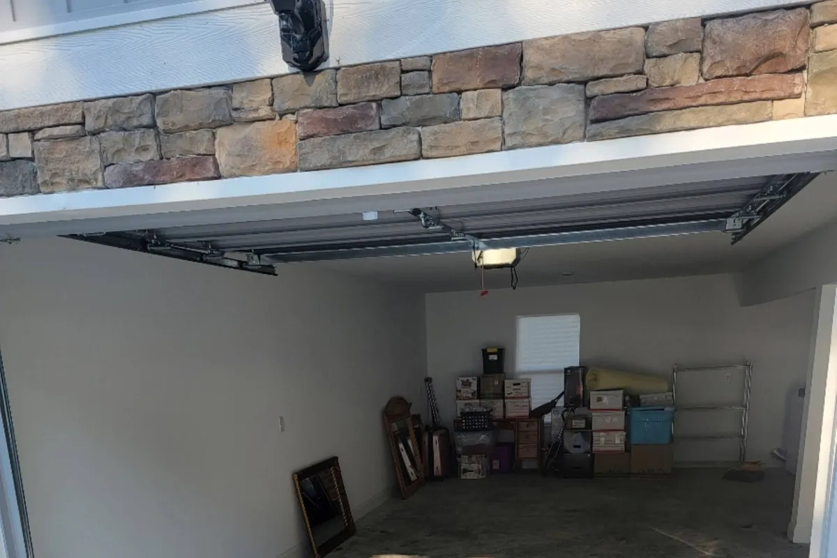 The image features a practical garage interior with stacked boxes and shelves, hinting at both storage potential and vehicle parking. The space feels organized and functional, supporting security and convenience for arrivals and departures.